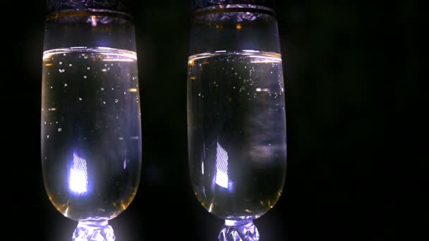 Champagne bouillonnant étant versé dans deux verres en cristal contre le noir — Video