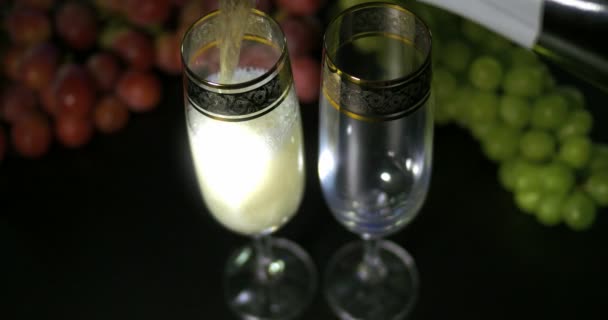 Champagne bollente versato in due bicchieri di cristallo contro boke backgroung nero — Video Stock