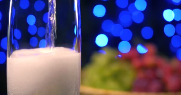 Champanhe borbulhante sendo derramado em dois copos de cristal contra boke backgroung preto — Vídeo de Stock