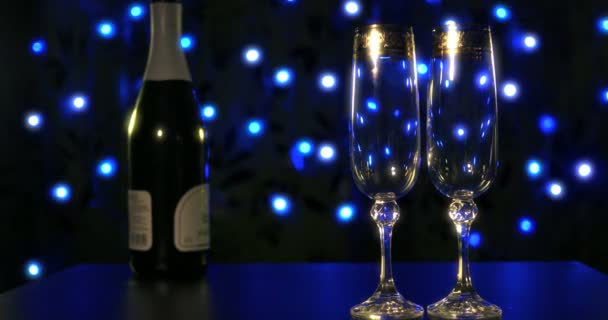 Порожні окуляри і пляшка шампанського на синьому фоні — стокове відео
