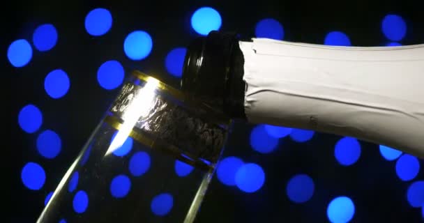 Бульбашкове шампанське вливають у два кришталеві келихи проти чорного фону — стокове відео