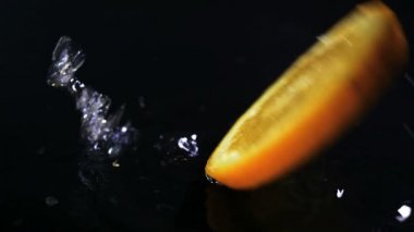 Yavaş hareket ile su düşen limon siyah yüzey üzerinde damla.