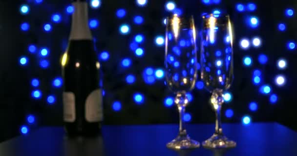 Порожні окуляри і пляшка шампанського на синьому фоні — стокове відео