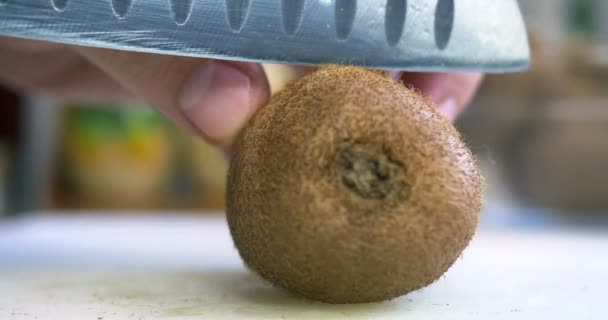 Main tranchant un kiwi avec un couteau, gros plan — Video