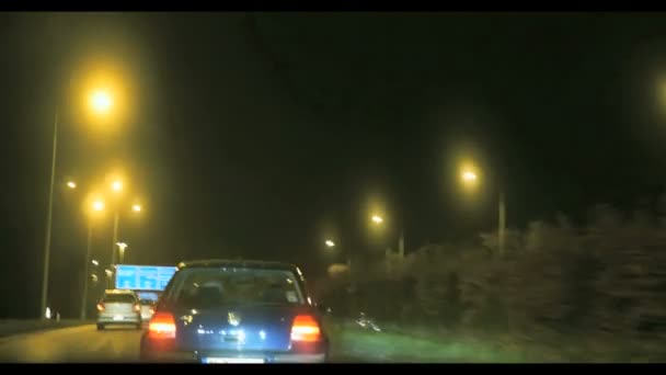 Прискорення на автомагістралі, хоча маленьке містечко в туманних хмарах вночі — стокове відео
