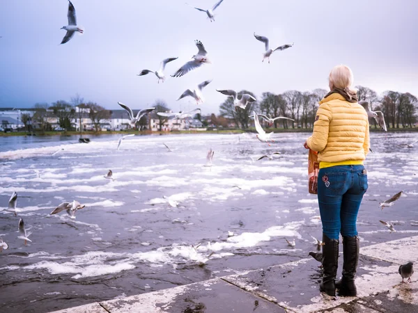 Glückliche Frau füttert Möwen am Flussufer — Stockfoto