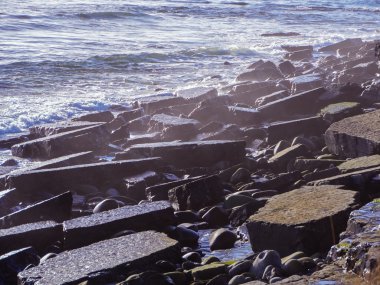 Deniz dalgaları plajda kayaya çarpıyor.
