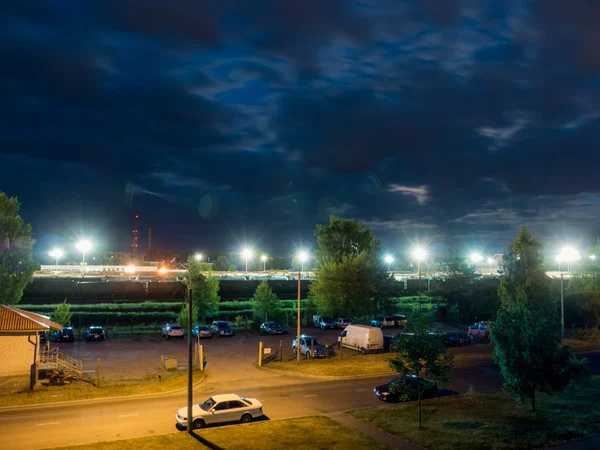 Aparcamiento nocturno con farolas y nubes oscuras — Foto de Stock