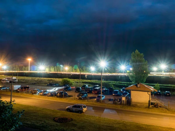 Parcheggio notturno con lampioni e nuvole scure Fotografia Stock