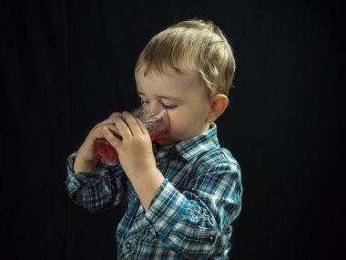 kid boy drinking juice. Studio photo 