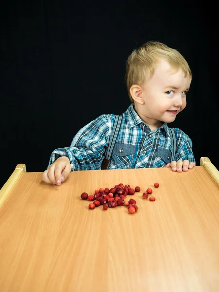 Baby boy eating barries. S — ストック写真