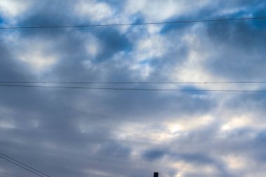 Bulutlu bir gökyüzünün arka planında elektrik kabloları.