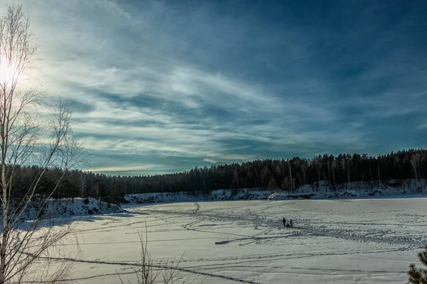 Une carrière gelée avec des arbres poussant sur son rivage, par une journée ensoleillée. — Photo