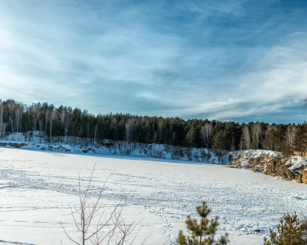 Uma pedreira congelada com árvores crescendo em um dia ensolarado brilhante. — Fotografia de Stock