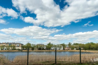 Metal bir çitin arkasında bir göl var, bulutlu bir gün..