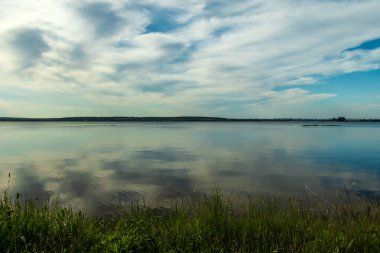 Güneşli bir günde aşırı gelişmiş göl kıyısı.