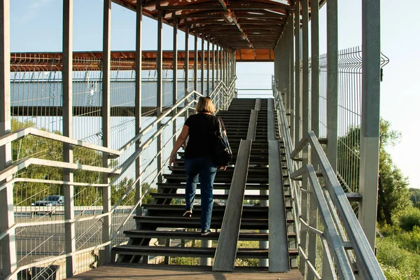 A woman climbs the steps of an overhead pedestrian crossing. The photo was taken in Chelyabinsk, Russia.