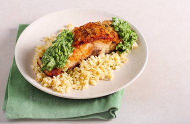 Bulgur buğdayının üzerine yeşil soslu sazan balığı filetosu.