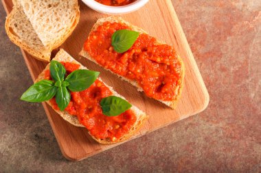 Ekmek dilimlerinin üzerine yayılmış kızarmış sebzeler.