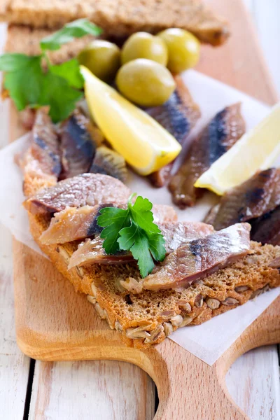 Smoked fish pieces on brown seed bread — Stock Photo, Image