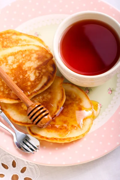 Pancakes with honey and cup of tea — Stock Photo, Image