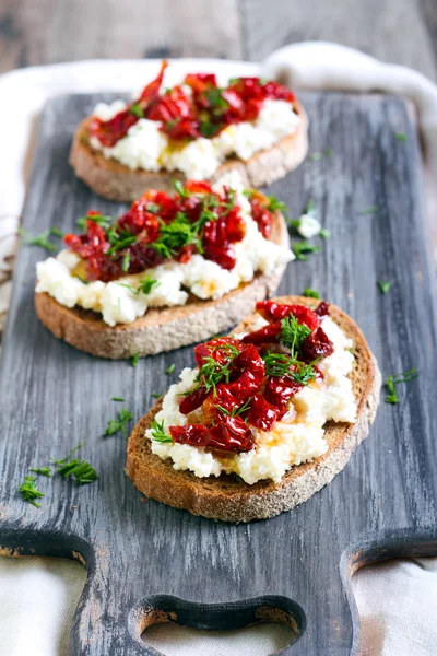 Bread slices with ricotta cheese and, sun dried tomatoes — Stock Photo, Image