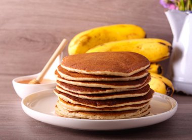 Olgunlaşmış muzlu krep tabakta, balla servis ediliyor.