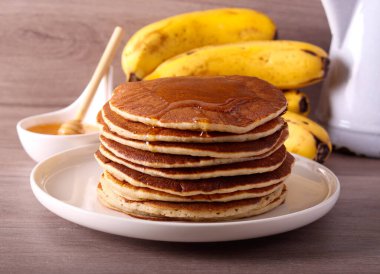 Olgunlaşmış muzlu krep tabakta, balla servis ediliyor.