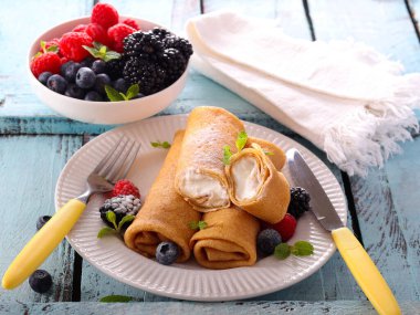 Krep ruloları ricotta ile dolu, karışık böğürtlen ile servis edilir.