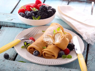 Krep ruloları ricotta ile dolu, karışık böğürtlen ile servis edilir.