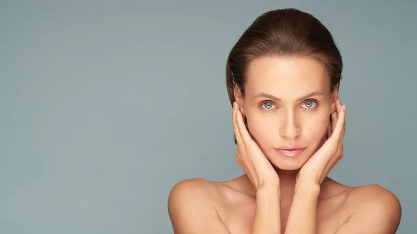 Mulher bonita com pele limpa e perfeita. Retrato de um modelo de beleza com um fundo azul natural, espaço de cópia. — Fotografia de Stock