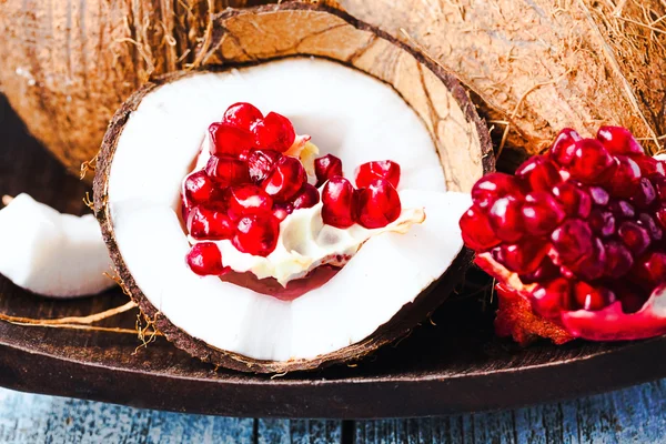 Fresh coconut and red garnet in a wooden bowl,blue background — Stock Photo, Image