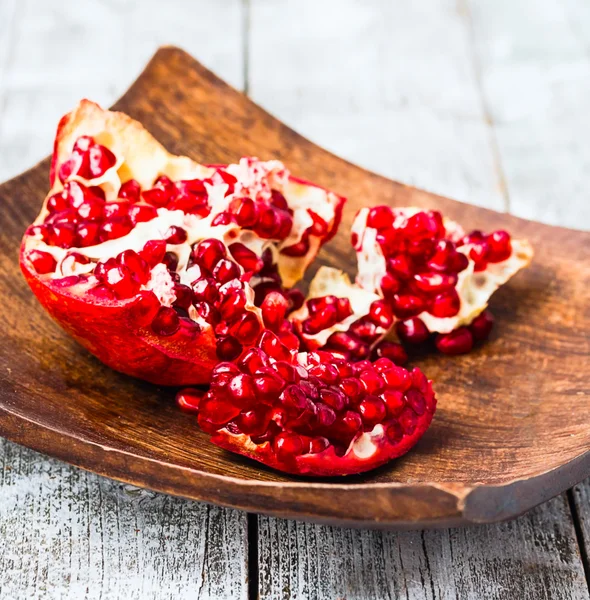 Ripe red  garnet in a wooden bowl,blue background — Stock Photo, Image