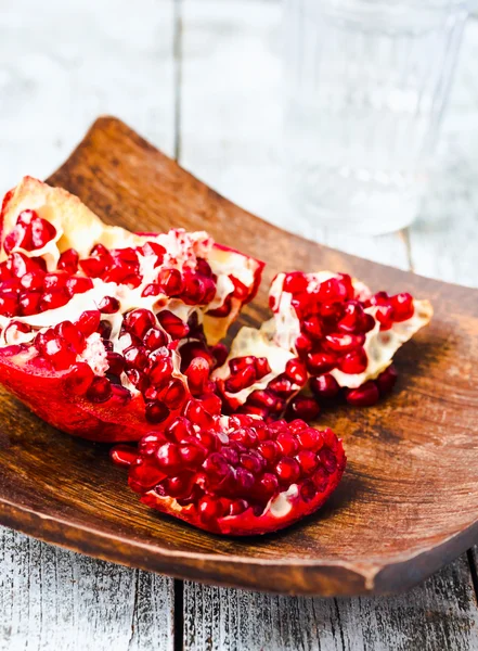 Ripe red  garnet in a wooden bowl,blue background — Stock Photo, Image