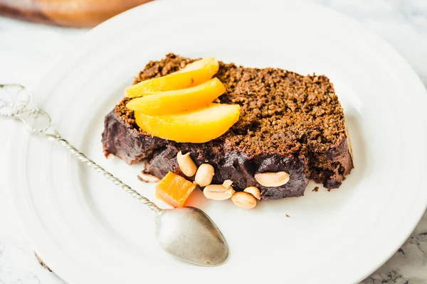 Piece of chocolate cake with pumpkin, nuts and fresh peaches on — Stock Photo, Image