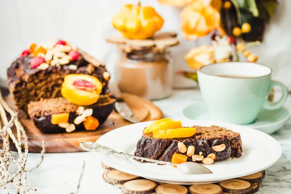 Piece of chocolate cake with pumpkin, nuts and fresh peaches on — Stock Photo, Image