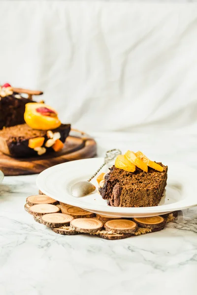 Piece of chocolate cake with pumpkin, nuts and fresh peaches on — Stock Photo, Image