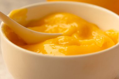 Limon kaymağı beyaz bir kasede. Yakın plan sarı arka plan. Yatay..