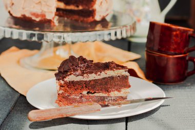 Beyaz tabakta üç dilim çikolatalı pasta. Lezzetli ev yapımı keklerle dolu bir masa. Mavi gri ahşap arkaplan.