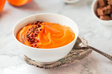 Balkabağı çorbası ve mermer masada organik kabaklar. Mevsimlik sonbahar yemekleri - Baharatlı balkabağı ve havuç çorbası.