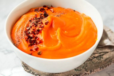 Kavrulmuş balkabağı ve havuç çorbası, siyah ve kırmızı biberli mermer kaplama biber. Yakın plan..