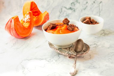 Kavrulmuş balkabağı ve havuç çorbası siyah ve kırmızı biber, mermer arka planda çavdar ekmeği. Geleneksel sonbahar ve kış yemekleri..