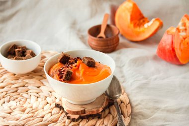 Lezzetli iştah açıcı balkabağı kremalı çorba kırmızı biber ile süslenmiş sonbahar konforlu arka plan konseptinde beyaz kasede servis edilir..