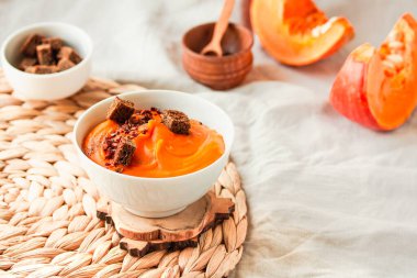 Bir kase lezzetli balkabağı çorbası, yanında kırmızı biber, çavdar ekmeği ve sonbahar konfor arka planında kızarmış ekmek. Geleneksel sonbahar ve kış yemekleri konsepti.