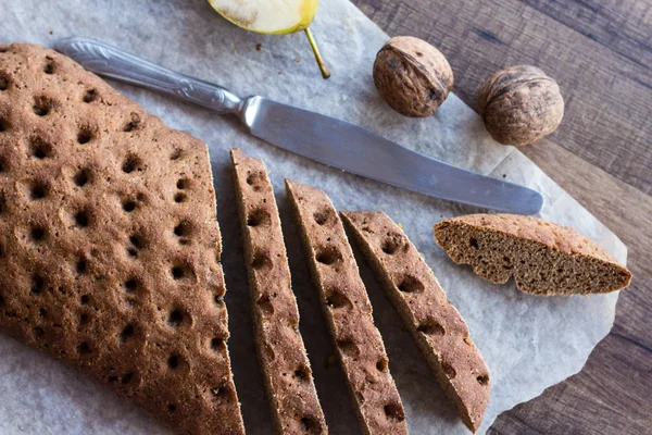 Sliced rye bread with a knife, walnuts, top view — Stock Photo, Image