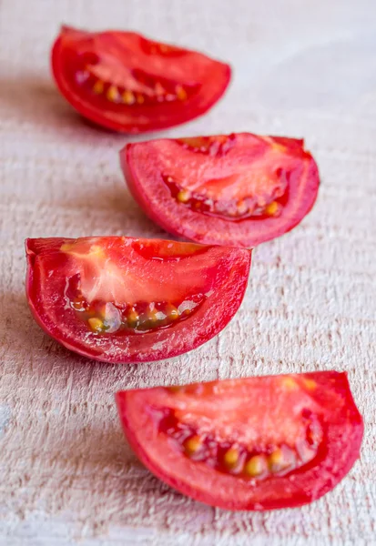 Сырые четверть красных помидоров на белой деревянной доске — стоковое фото