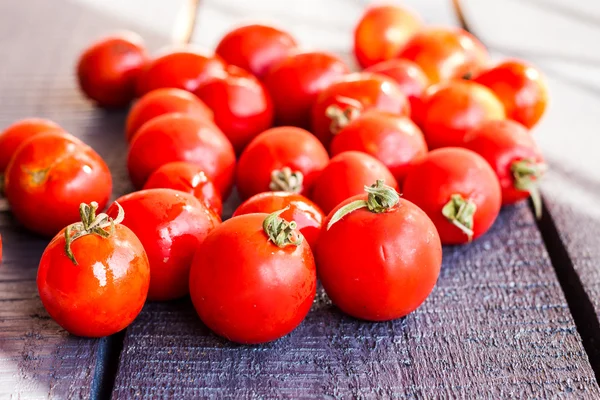 Juicy tomatoes cherry on dark wooden board — Stock Photo, Image
