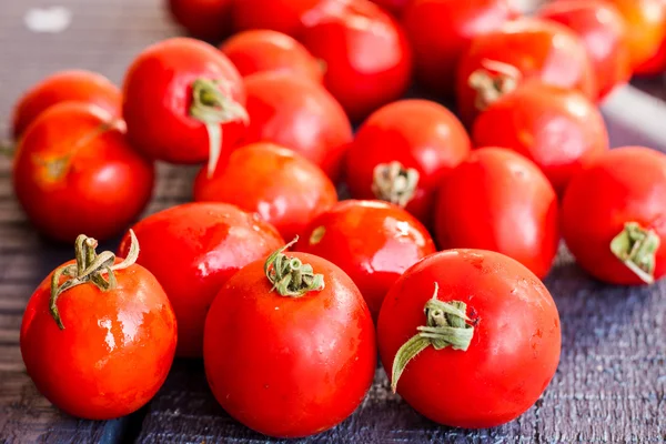 Red juicy tomatoes cherry on dark wooden board — Stock Photo, Image