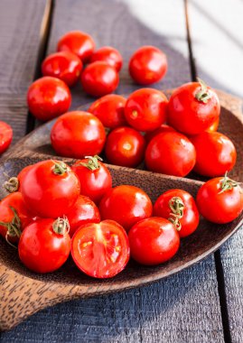 kahverengi ahşap tabak içinde kiraz kırmızı sulu domates 