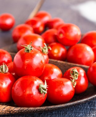 kahverengi ahşap tabak içinde kiraz kırmızı sulu domates 